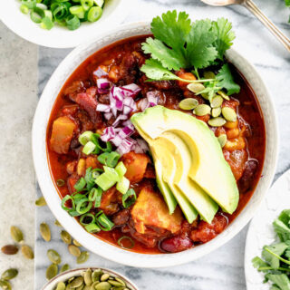 Chili in a bowl with a fan of avocado slices on it