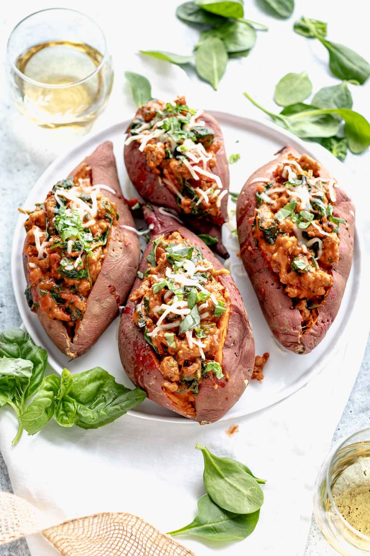 a platter with four stuffed sweet potatoes on it and a glass of wine