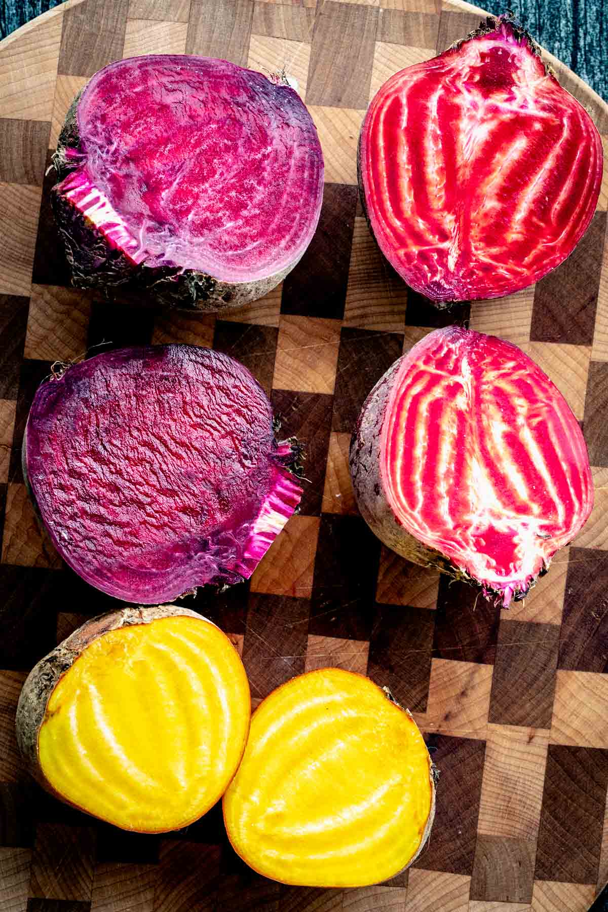purple, gold, and red and white striped beets on a checkered cutting board