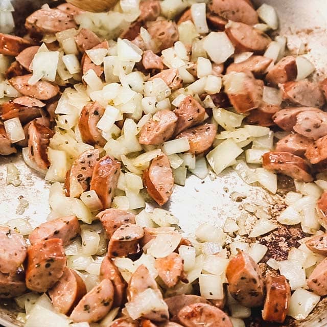 the onions and sausage are browning in the skillet