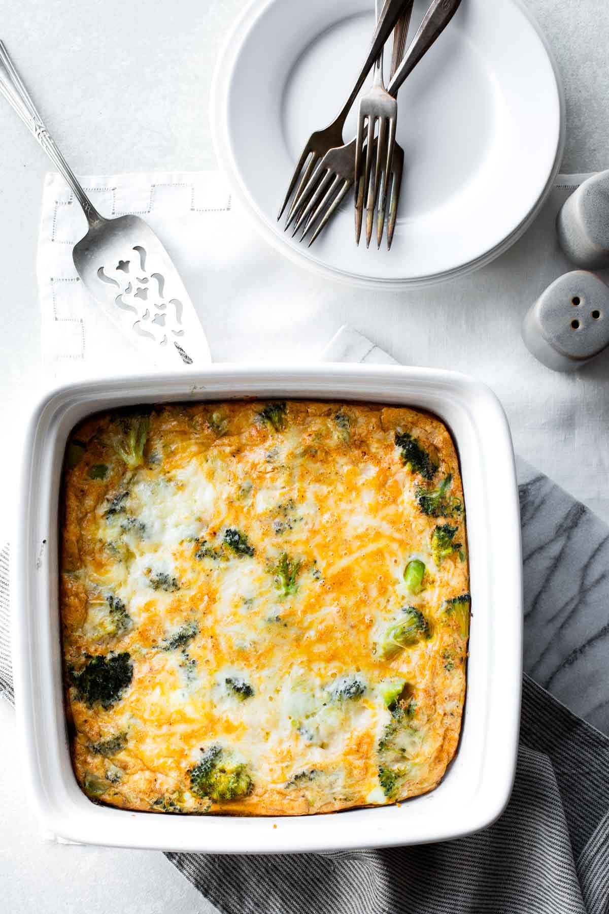 A white square casserole dish with egg bake in it from overhead on a white tablecloth 