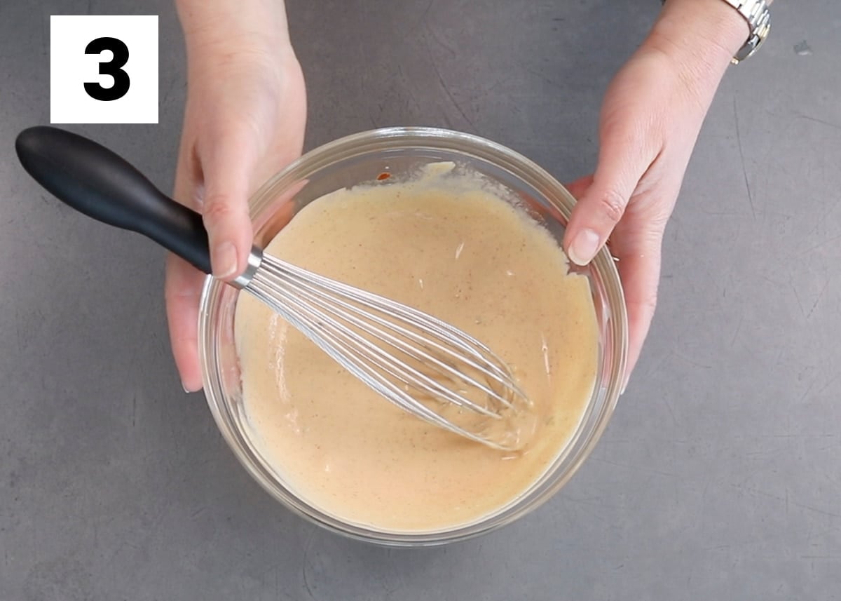 the special sauce in a glass bowl with a whisk, two hands holding it