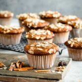A bunch of muffins sitting on a table with carrots and nuts on the table
