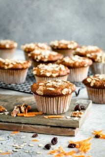 A bunch of muffins sitting on a table with carrots and nuts on the table
