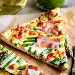 a slice of asparagus pizza with prosciutto on it