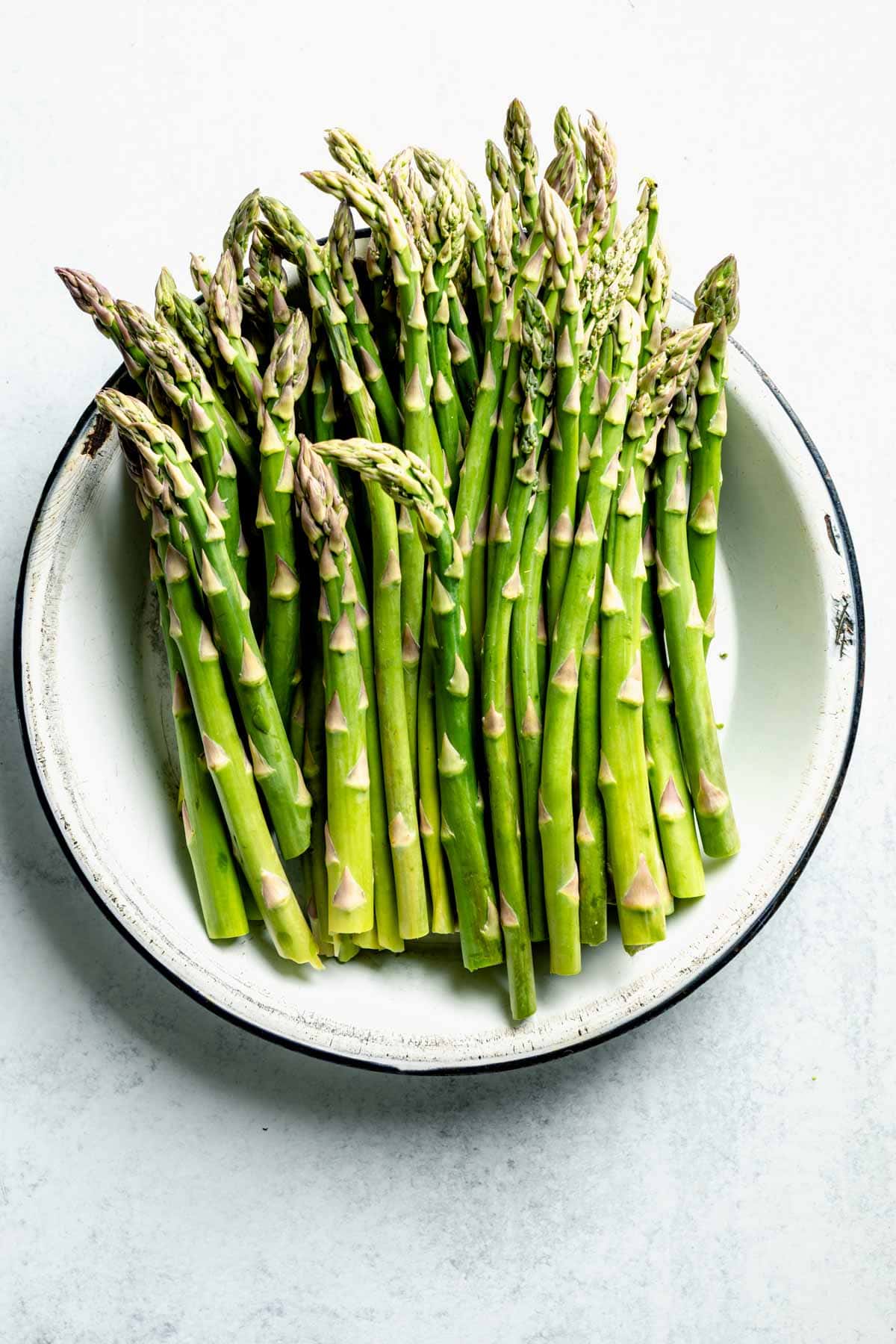 A large bowl of fresh green asparagus stalks.