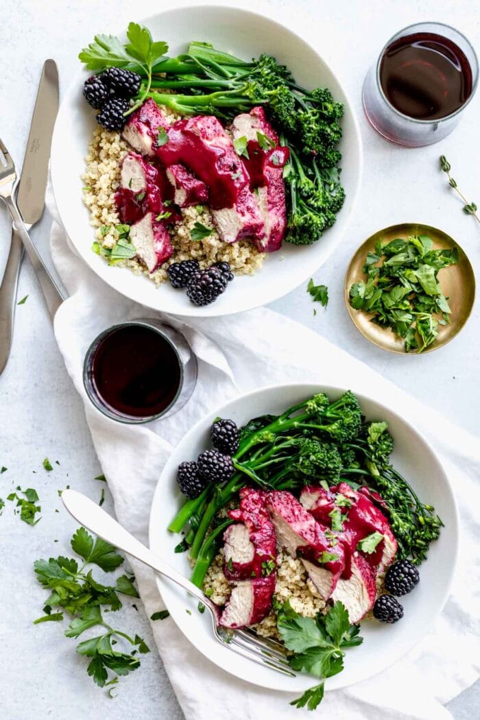 blackberry chicken in two bowls with red wine overhead on a white table