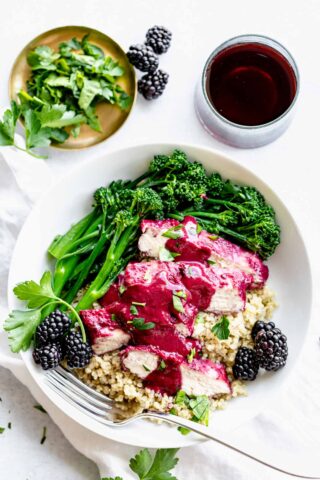 a bowl with chicken, blackberry sauce and broccolini