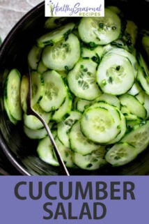 cucumber salad in a black bowl with spoon