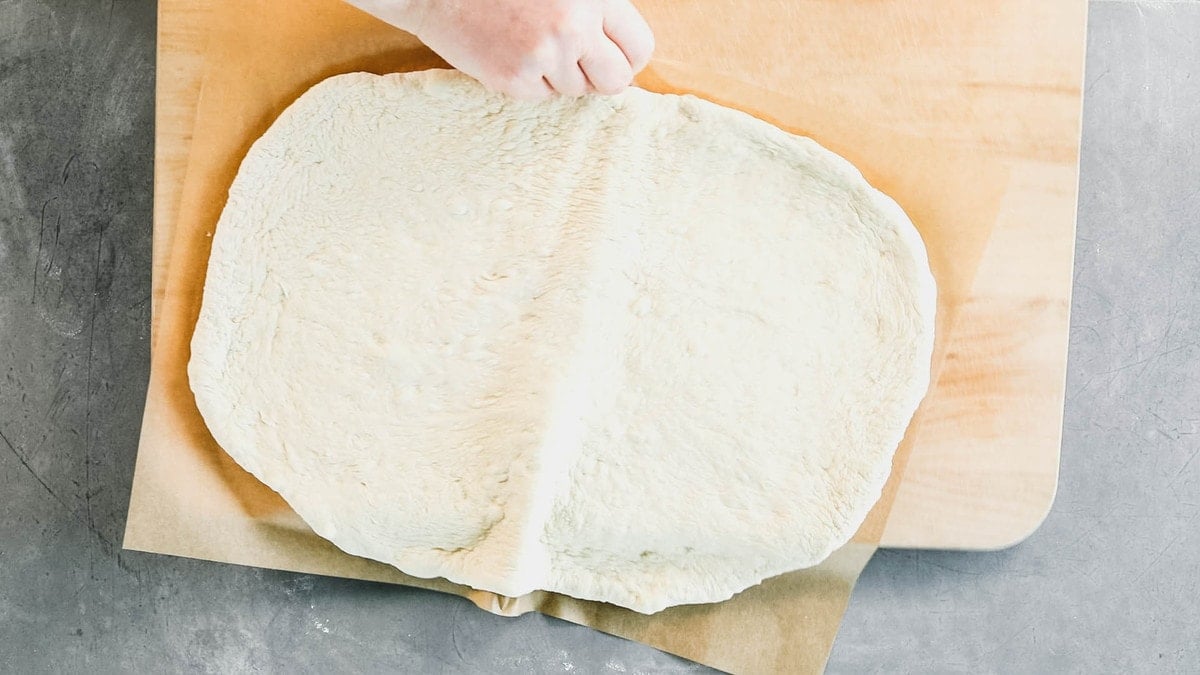 sliding the pizza on the parchment onto the cutting board