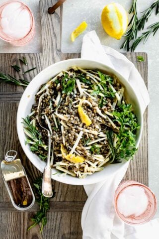 lentil and celery root salad with herbs in a bowl from overhead with pink water glasses