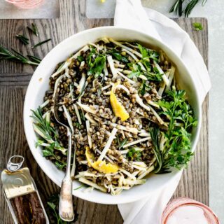lentil and celery root salad with herbs in a bowl from overhead with pink water glasses