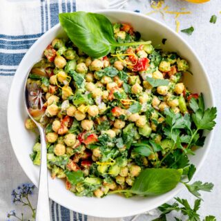 overhead of bowl of chickpea salad with herb sprigs to garnish