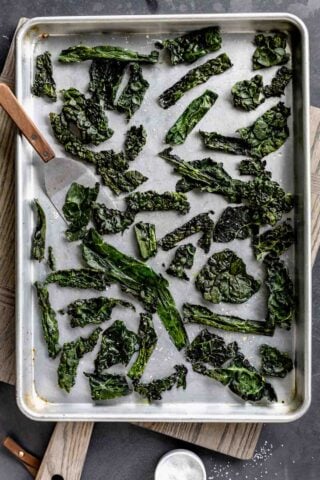 kale chips on a baking sheet with a small spatula