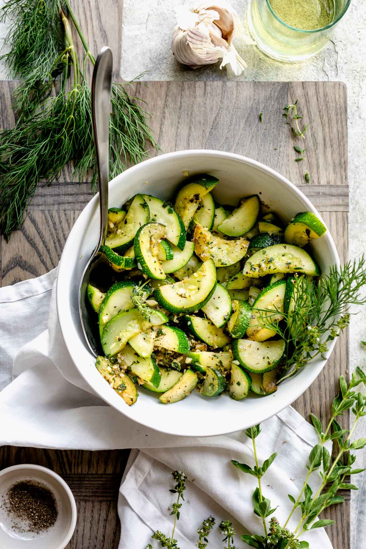 a white bowl with zucchini and herbs