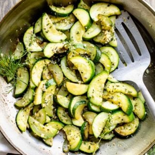a close up of zucchini in a skillet with herbs and garlic