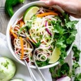 kohlrabi slaw with lime and cilantro in a bowl with a hand holding the bowl