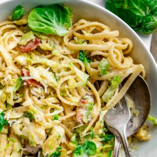 the carbonara pasta with brussels sprouts up close in the bowl with a few individual leaves on top
