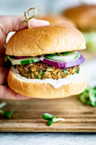 Veggie burger in a persons hand with a toothpick in the top