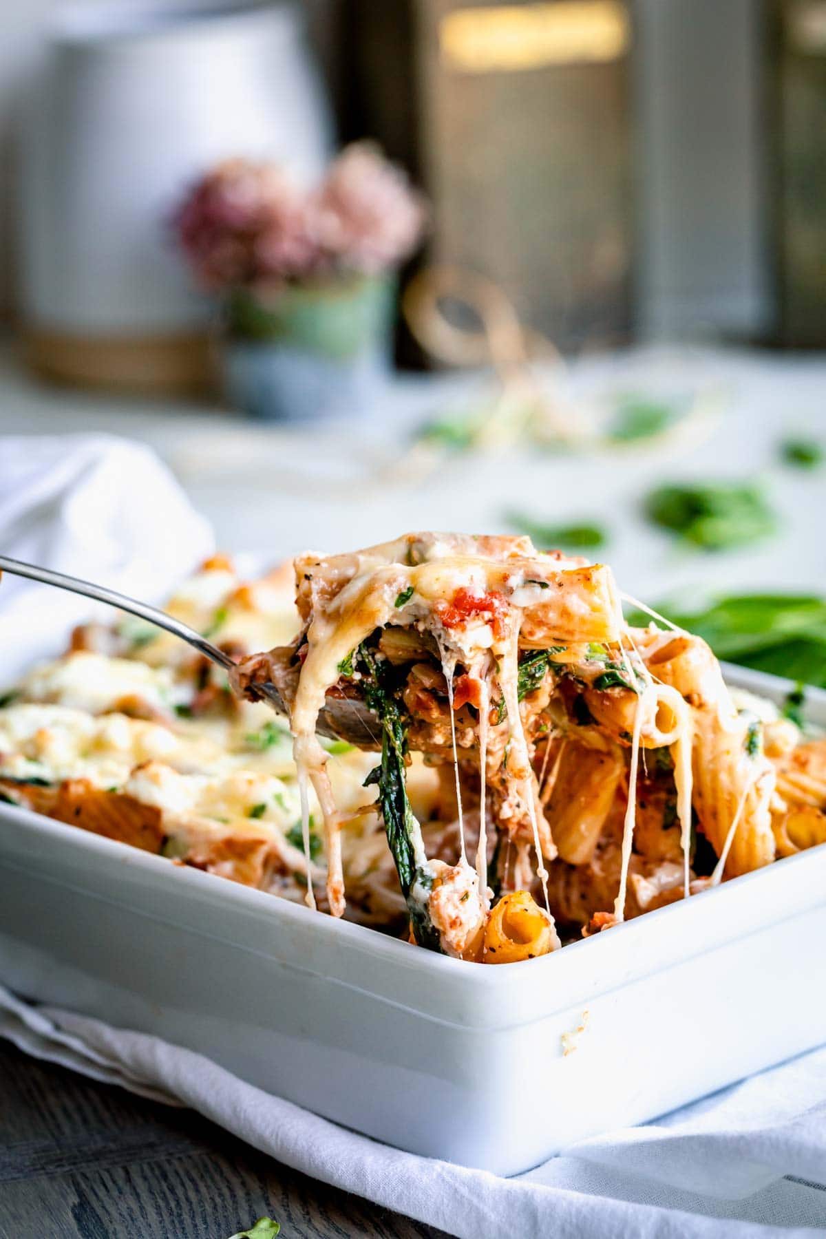 a scoop of cheesy pasta bake with cheese pull
