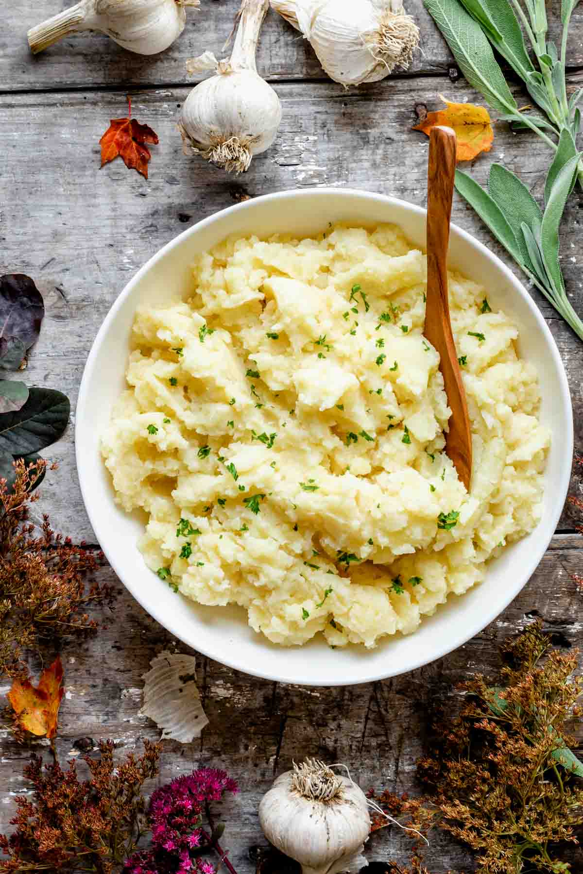 mashed potatoes with garlic on a gray wooden table with fall flowers and foliage