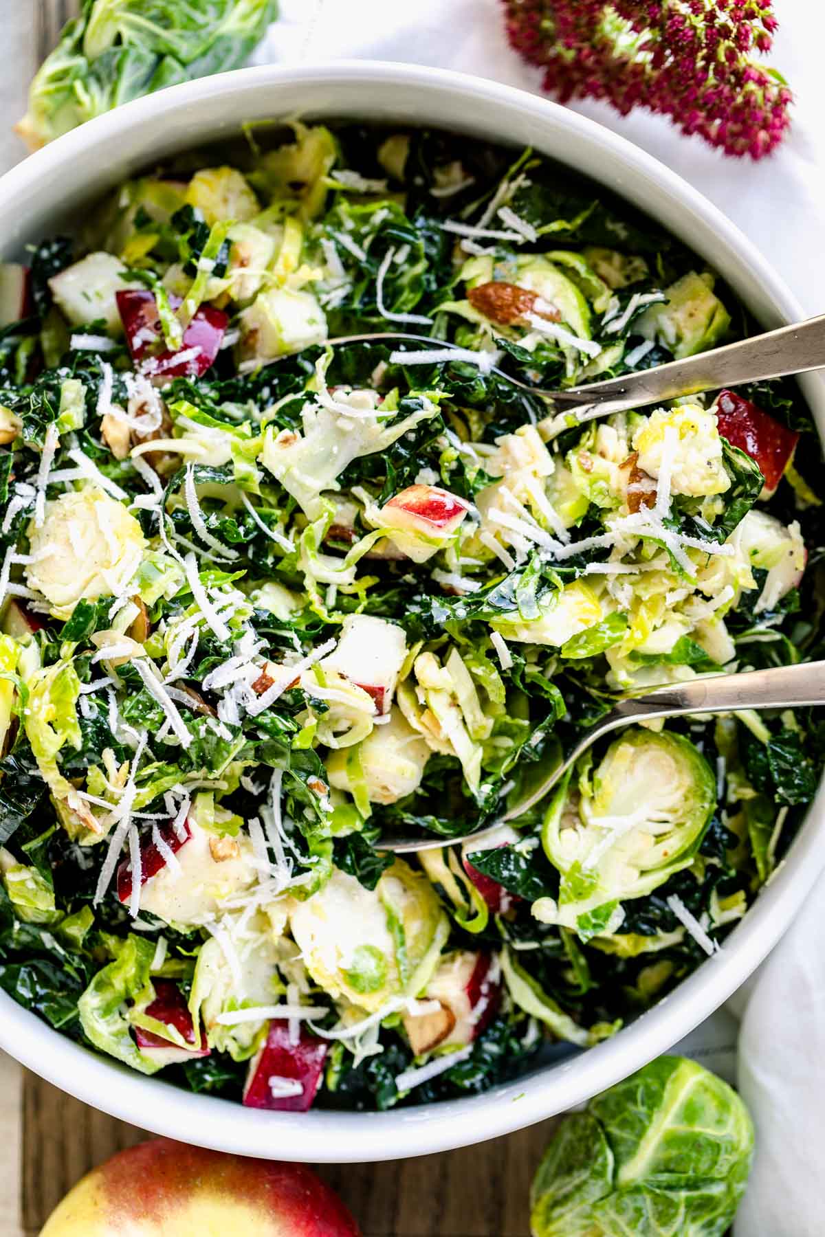 Shaved brussels sprouts salad with parmesan in white circular bowl with serving wear