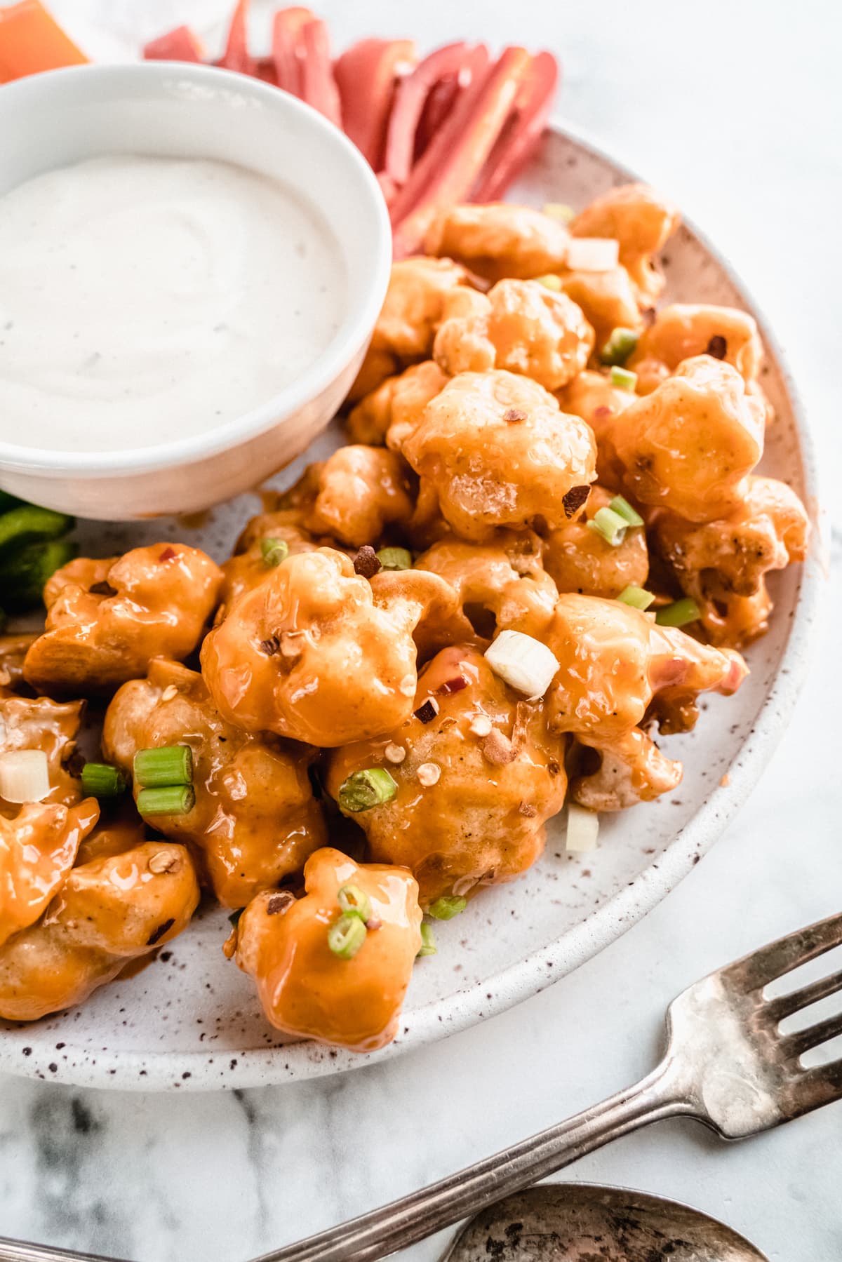 white platter of bang bang cauliflower with dip and veggies