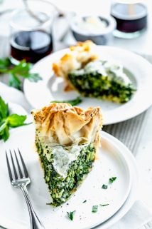Slice of spinach feta filo pie on a circular white plate