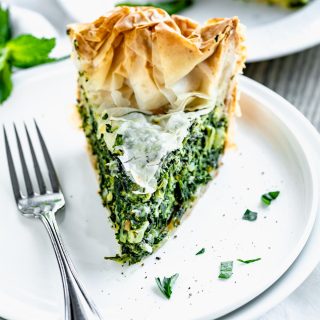 slice of spinach feta filo pie on circular white plate with fork