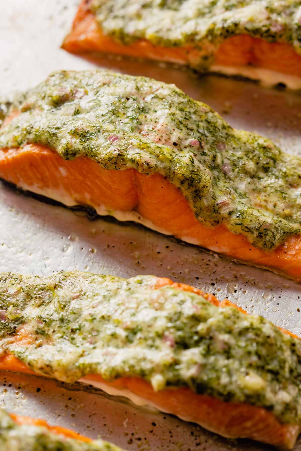baked salmon topped with a creamy herb sauce on a baking sheet