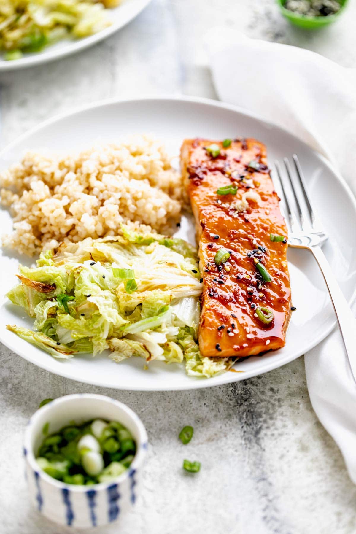 maple glazed salmon filet with sauteed napa cabbage and brown rice on circular white plate