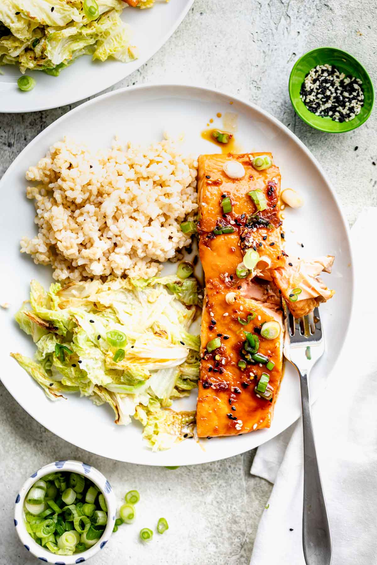 overhead shot of maple glazed salmon filet with sauteed napa cabbage and brown rice on circular white plate
