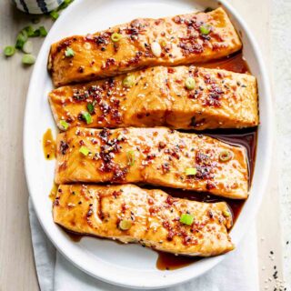 four portions of maple glazed salmon on a white oval platter
