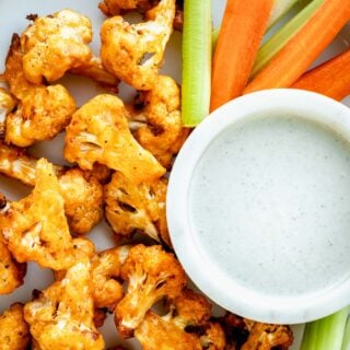 up close shot of air fryer buffalo cauliflower wings with celery and carrot sticks and dipping sauce