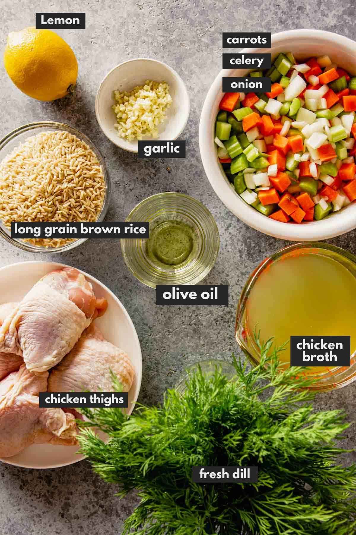 dry rice, a lemon, mirepoix, raw chicken thighs, broth, and fresh dill measured out and set on a counter