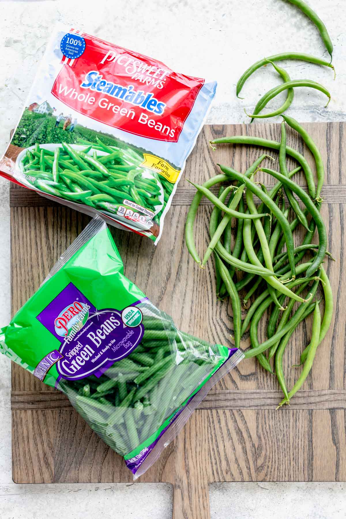 bagged green beans, frozen and fresh on a cutting board from overhead