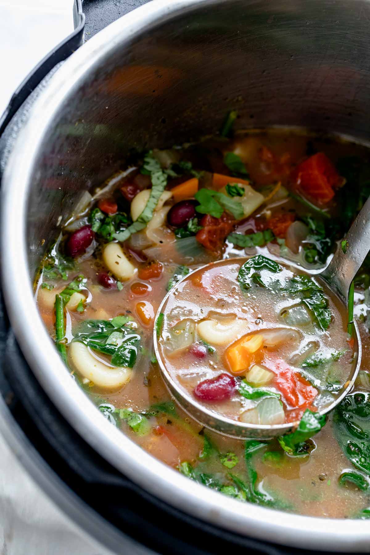close up of minestrone soup in ladle
