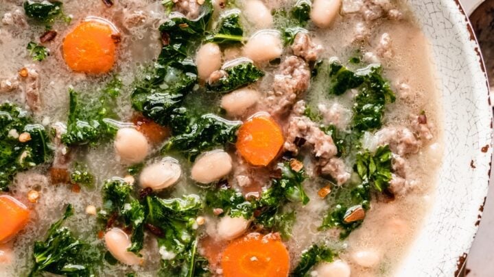 Sausage Kale soup with carrots and white beans in bowl
