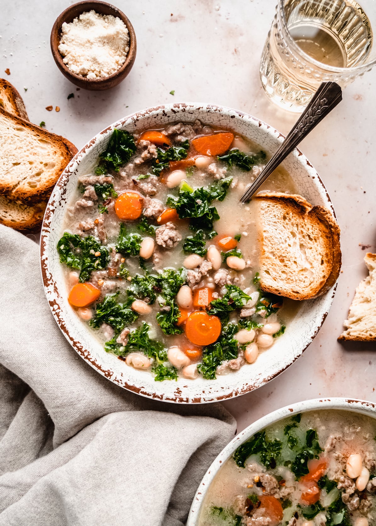 Sausage and Kale soup in two bowls with crusty bread in bowl