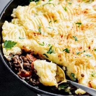 close up of lentil shepherd's pie recipe in cast iron skillet with a scoop in a spoon