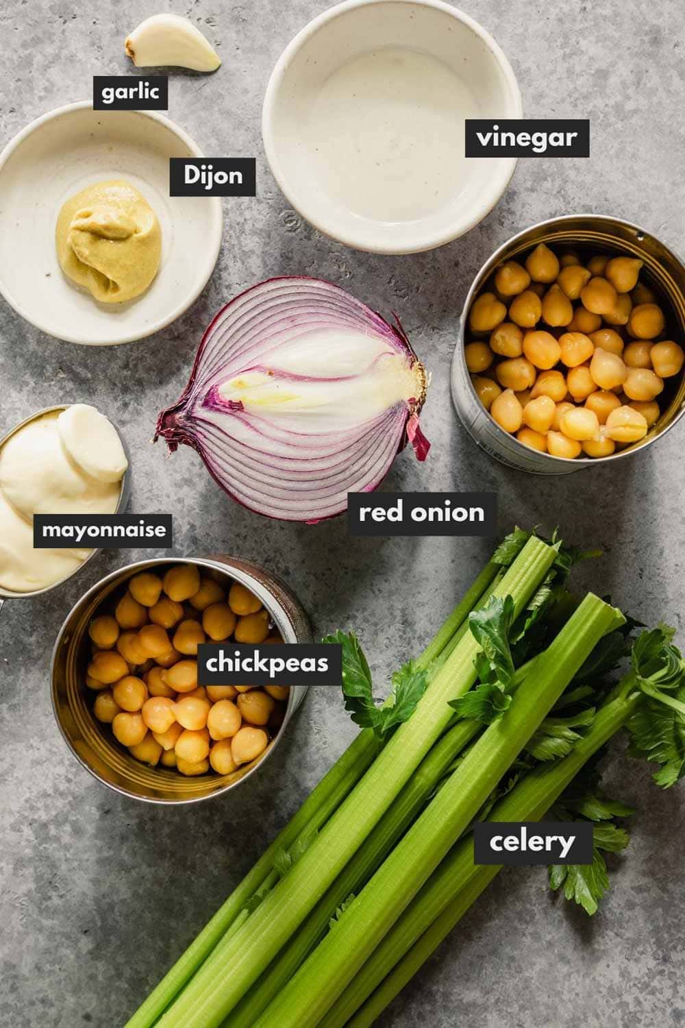 red onion, celery, chickpeas, dijon, garlic, mayo, and vinegar measured out and arranged on a table
