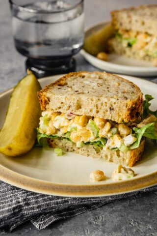 chickpea tuna salad on a white plate with a pickle spear