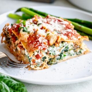 close up of a slice of baked vegetable lasagna on circular white plate.