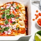 Baked turkey enchiladas in white casserole dish.