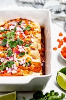 Baked turkey enchiladas in white casserole dish.