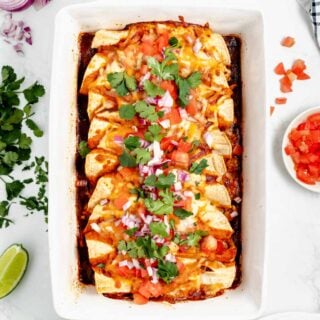overhead shot of healthy cheesy turkey enchiladas in white casserole dish.