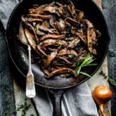 top view of Saut&eacute;ed portobello mushrooms in a black skillet with a spoon.