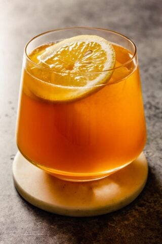 short rocks glass filled with an amber-hued cocktail and lemon wheel