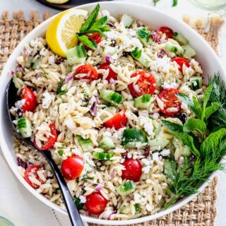 Close up of Orzo Pasta salad in a white bowl on a table.