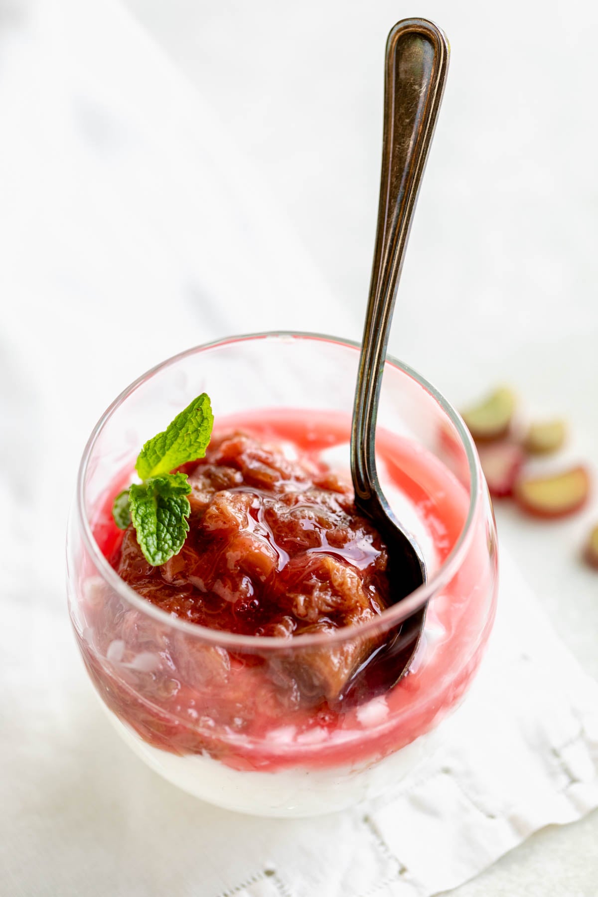 a glass with yogurt topped with compote with a spoon in it